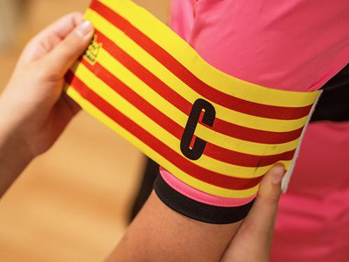 A captain's band being placed on an athlete's arm.