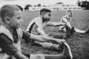 Young diverse boys stretching before sports practice in black and white image.