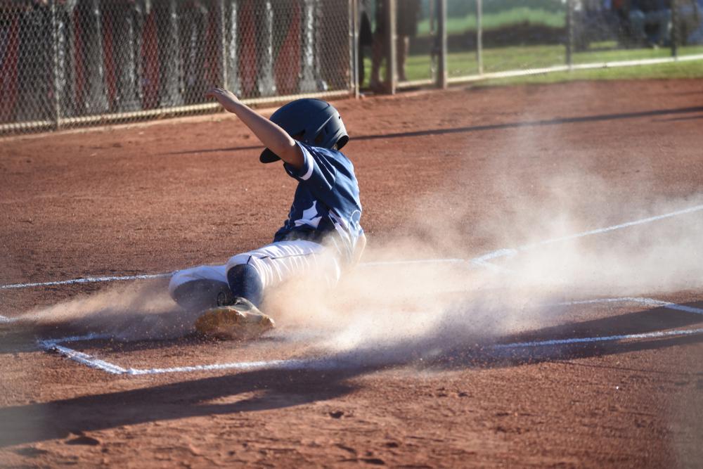 Young boy sliding into home base.