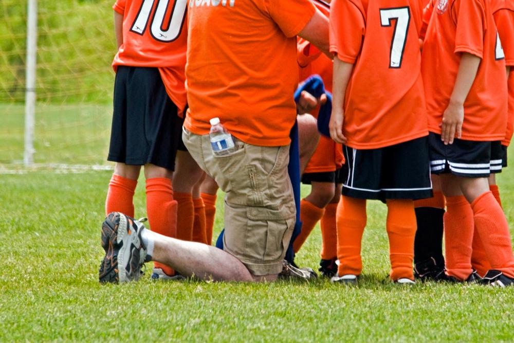 Coach kneeling with young soccer team.