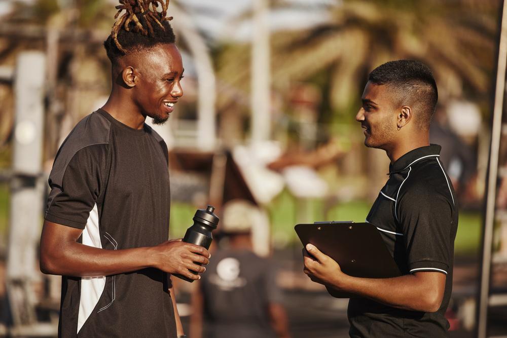 Young male athlete with coach and clipboard.