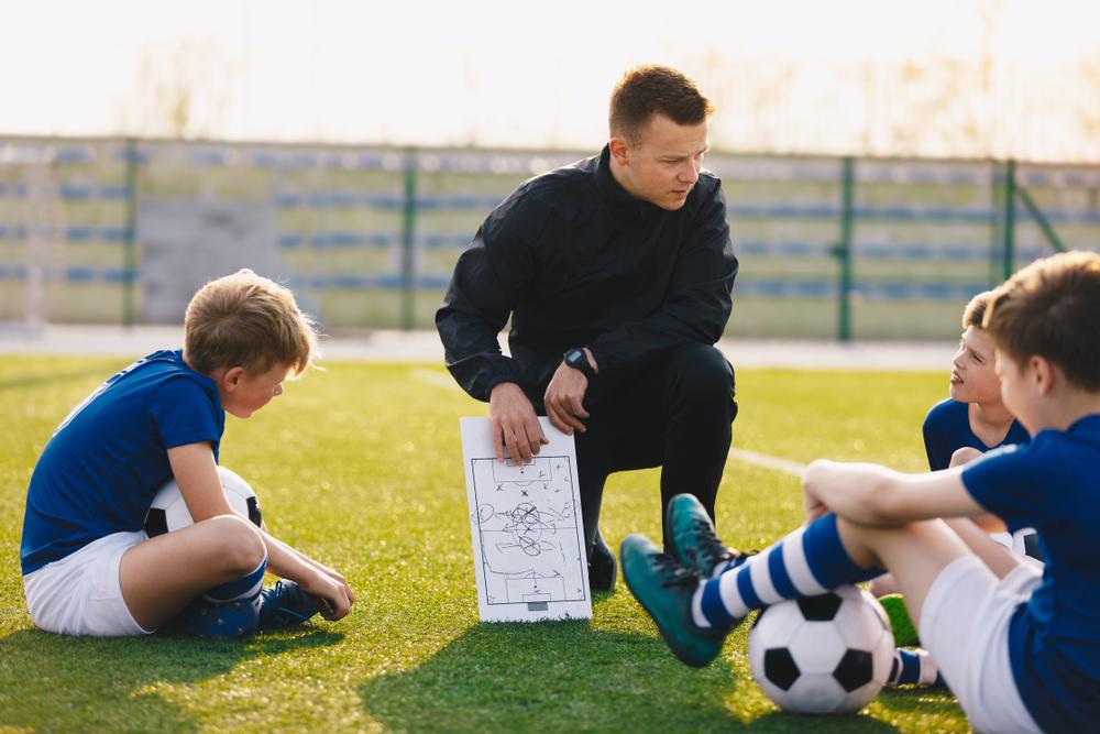 Soccer coach sharing a play with his team.