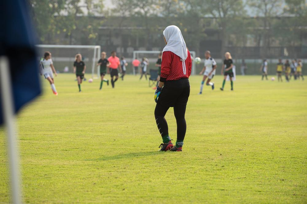 Young woman in hijah playing soccer.