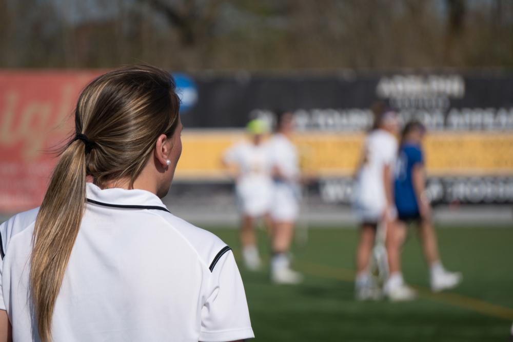 View from behind of female coaching yelling at team on field.