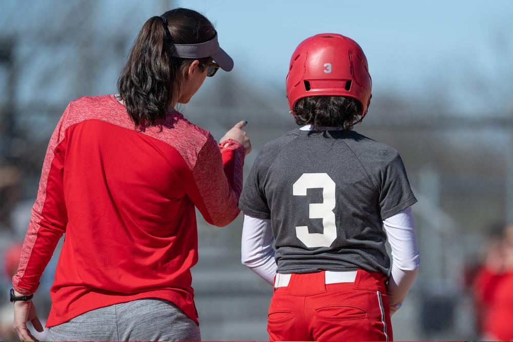 Female softball coach talking to youth athlete.