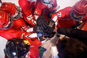 Ice hockey team hands in a huddle.
