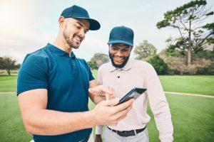 Two men in golf polos looking at a phone together.
