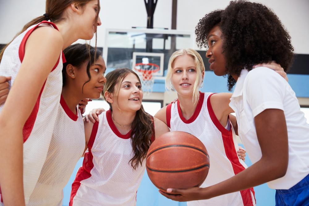 Female coach talking to female young basketball team.