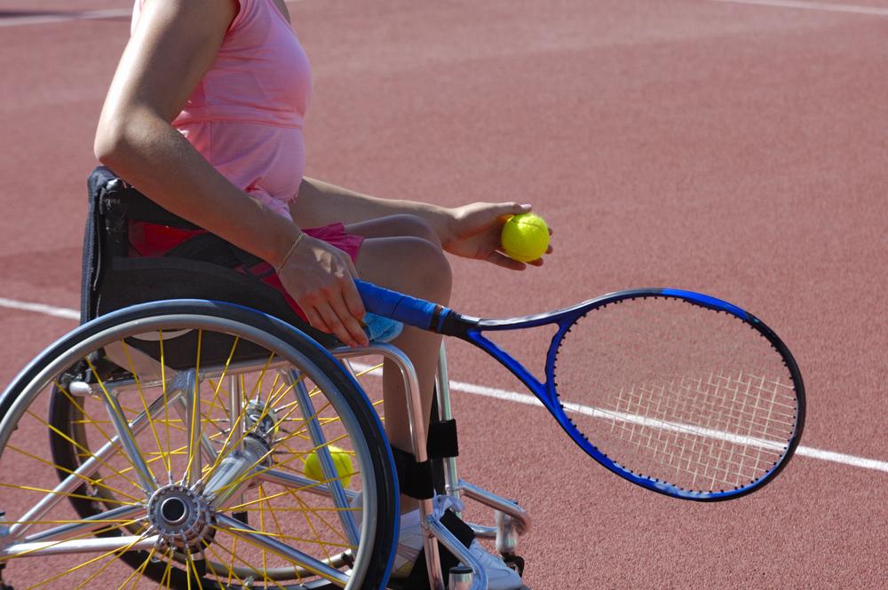 Woman in wheelchair playing tennis.