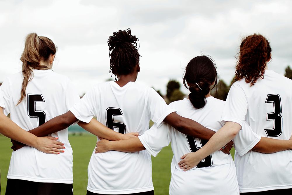 Team of diverse teen soccer players arm in arm.