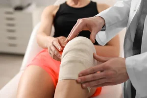 Close up of a doctor's hands on a wrapped knee of an athlete.