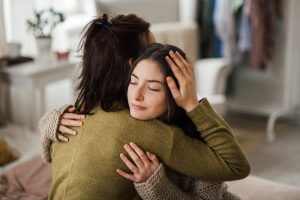 A mom and teenage daughter hugging.