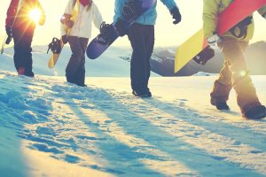 Snowboarders walking on snow.