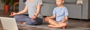 Parent and child meditating on yoga mat.