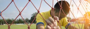 kid in yellow jersey hanging on to net