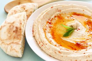 Plate of hummus next to cut up pita.