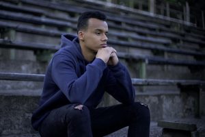 Teen boy sitting on bleachers thinking pensively.