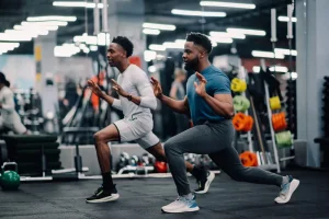 An athletic trainer working out with a young male athlete in a gym.