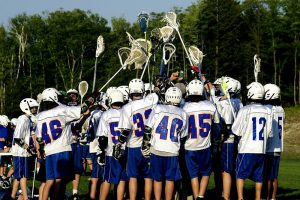 Lacrosse team huddled with sticks in the air.