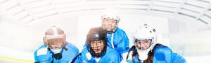 Young hockey players posing in full gear on ice.