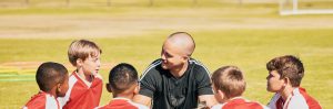 Coach and young soccer team in a huddle.