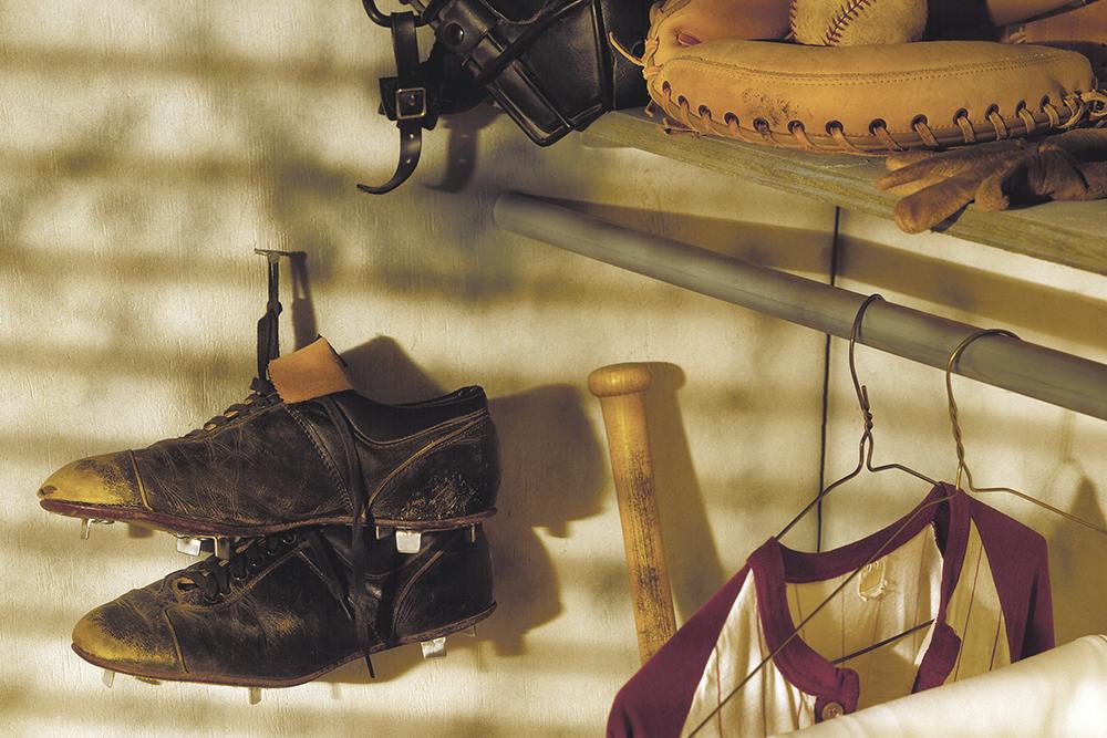 Baseball cleats and other gear hanging in a closet.