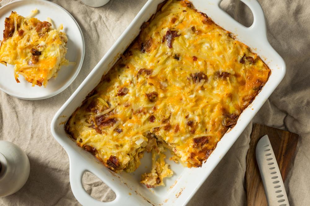 Breakfast casserole in white dish with a piece cut out.