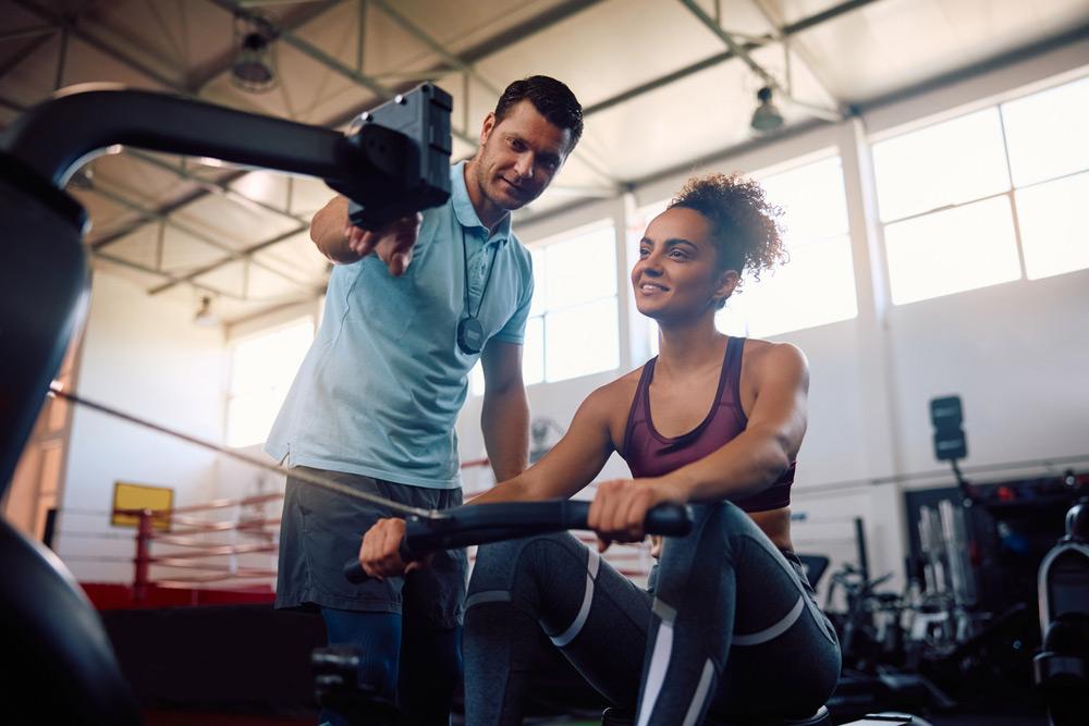 Coach assisting athlete on a rowing machine.