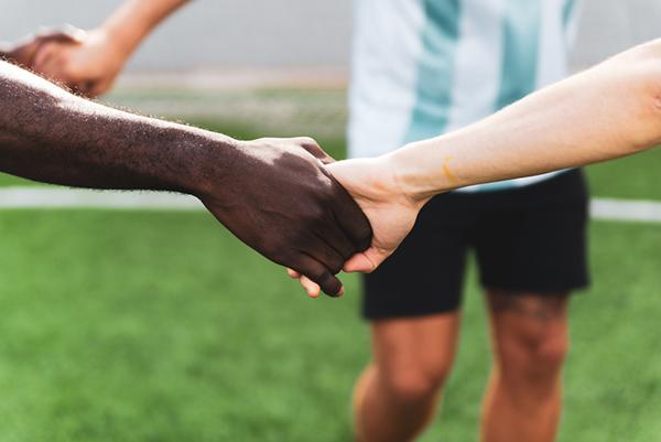 Close up of two soccer teammates holding hands.