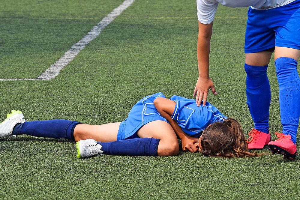 Injuried female teen soccer player on the field.