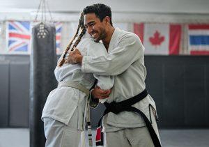 Karate coach hugging young female student.