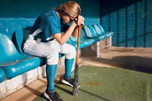 Female softball player upset in dugout.