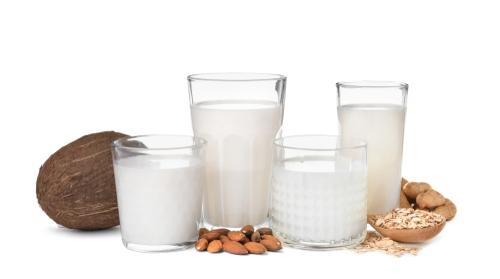Alternative milks in glass next to what they are made out of, including coconut, almonds, and rice.