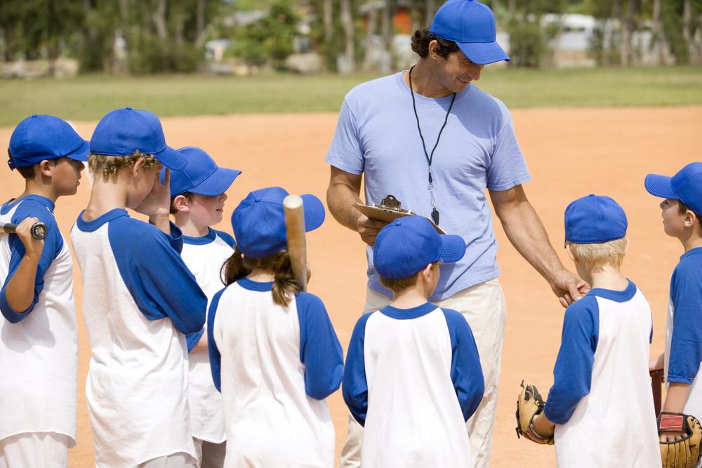 Boys youth baseball team coach talking with his team's players