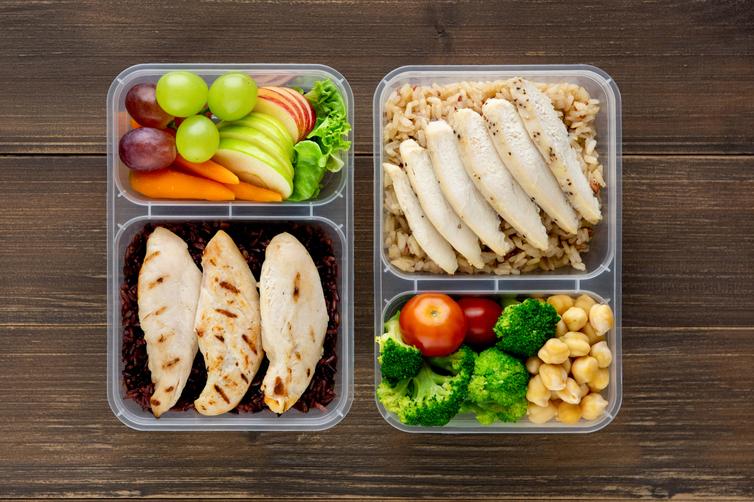 A balanced nutrient-dense meal of fruit, vegetables, rice, and chicken in separate containers.