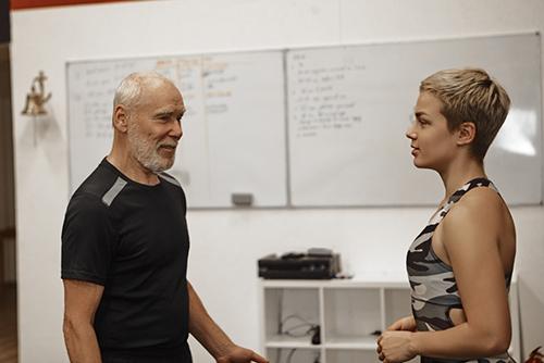 Older male coach talking to a younger female athlete.