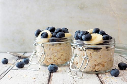 Two small glass jars of overnight oats topped with blueberry and banana.