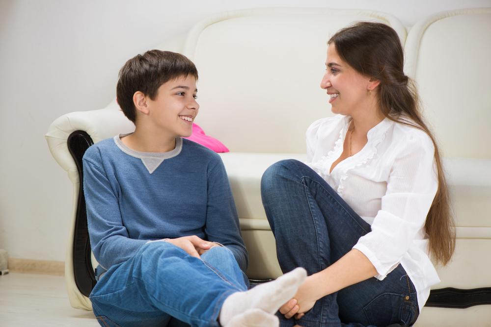 Mom talking to teen son near couch.