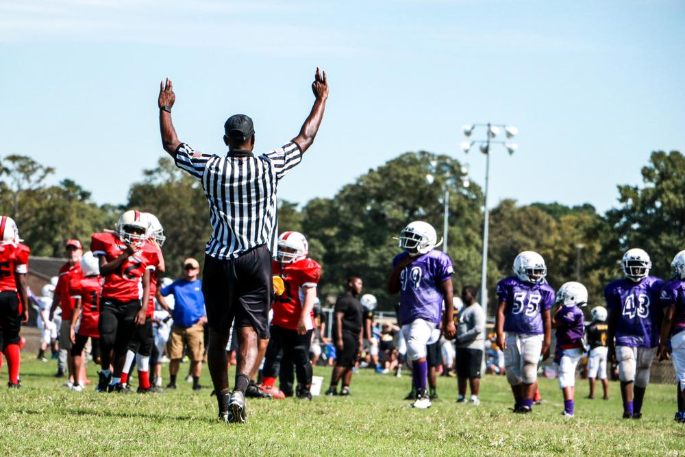 Referee with hands in the air during youth football game.