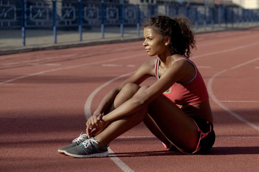 Young female athlete sitting on track.