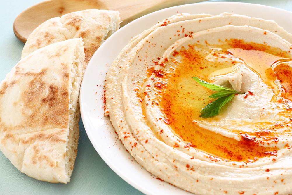 Plate of hummus next to cut up pita.