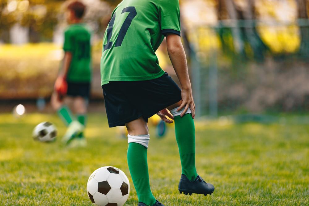 Soccer playing holding knee on field.