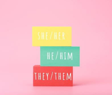 Blocks with pronouns written on them incuding he/him, she/her, and they/them.