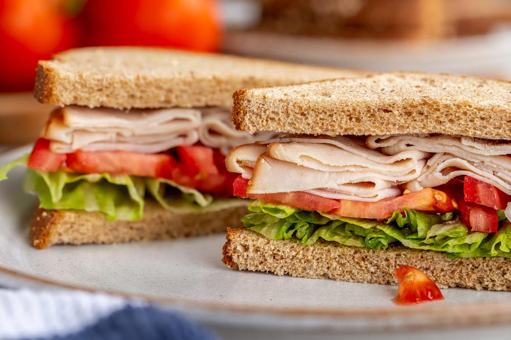 Turkey sandwich with lettuce and tomato on whole wheat bread.
