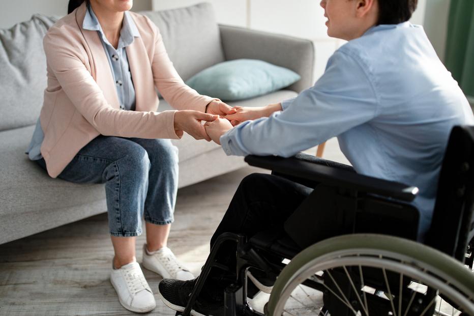 Therapist with young man in wheelchair.