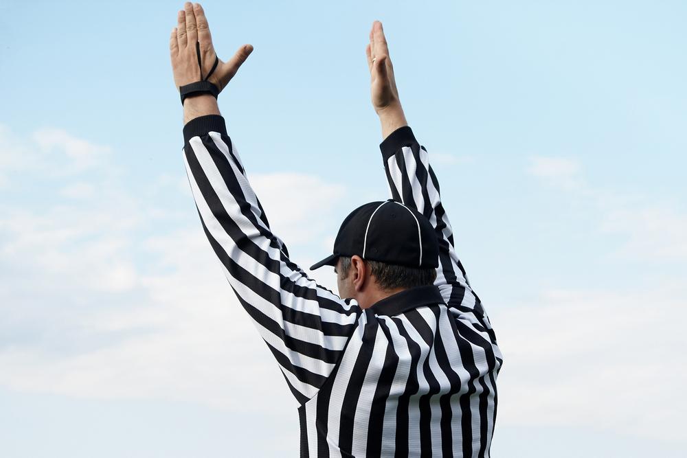 Referee with hands in air.