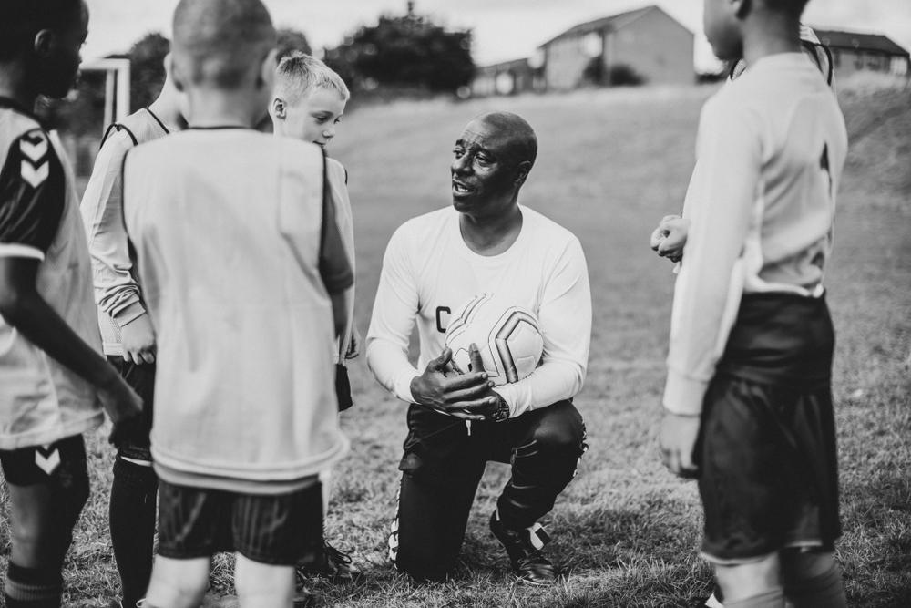 Coach of youth soccer team talking to team in a huddle.