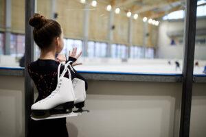 coping with quarantine White girl looking at skating rink while holding figure skating skates.