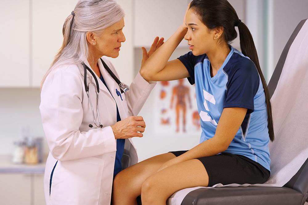 Teen girl soccer player visiting a woman doctor.