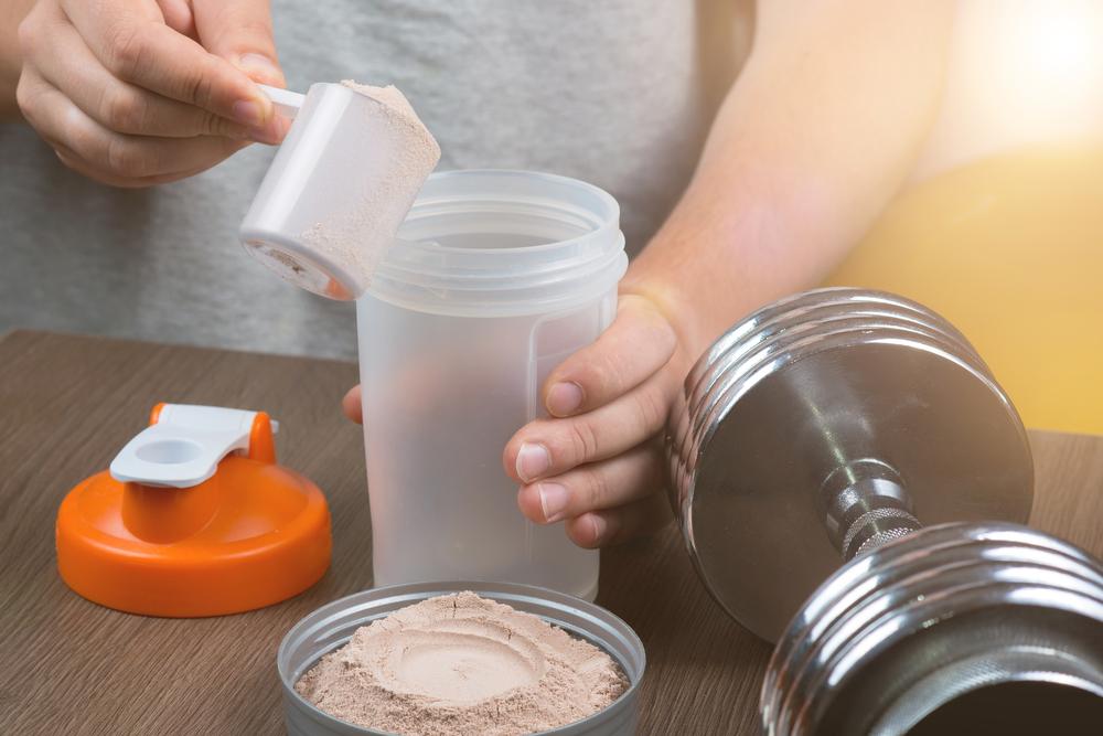 Close up of teen pouring powder supplement into water bottle.